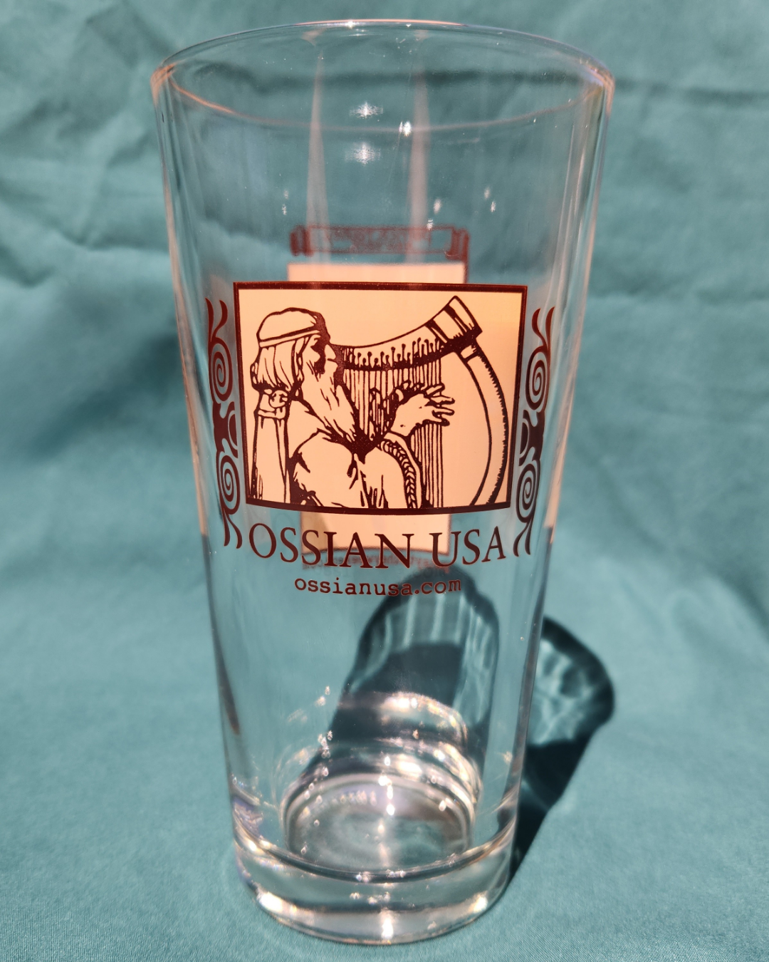Clear glass with Ossian USA logo on a teal fabric background