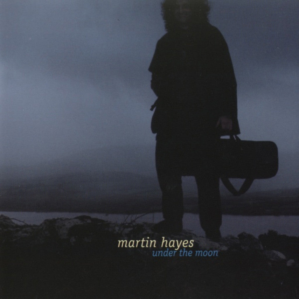 Album cover with silhouette of a person holding a violin case against a dark, misty landscape, featuring the text 'martin hayes under the moon'.